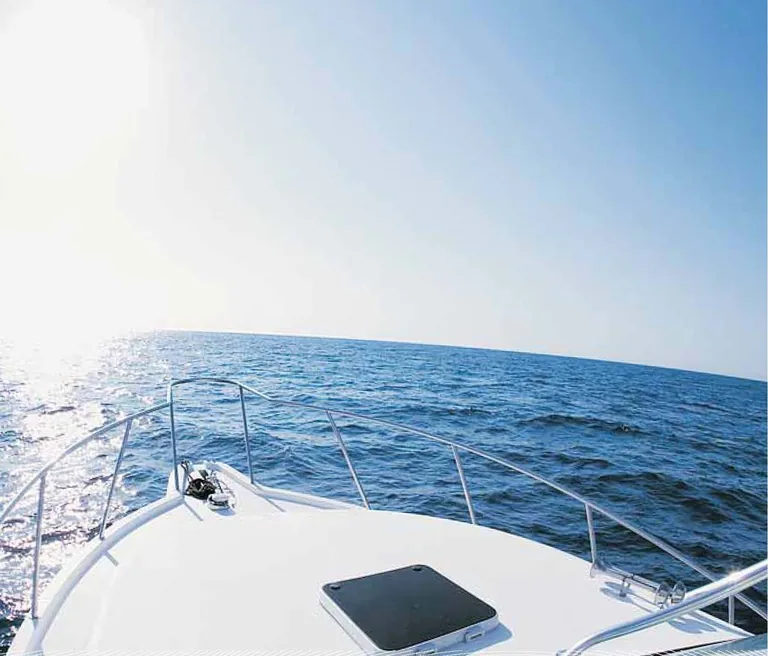 Illustrative photograph, not the development: the bow of a yacht heading out over open blue sea under a bright sky
