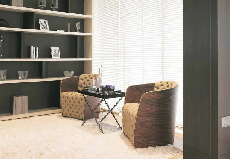 Photograph from the developer’s brochure: a study corner with two armchairs, a side table and open shelving beside a window